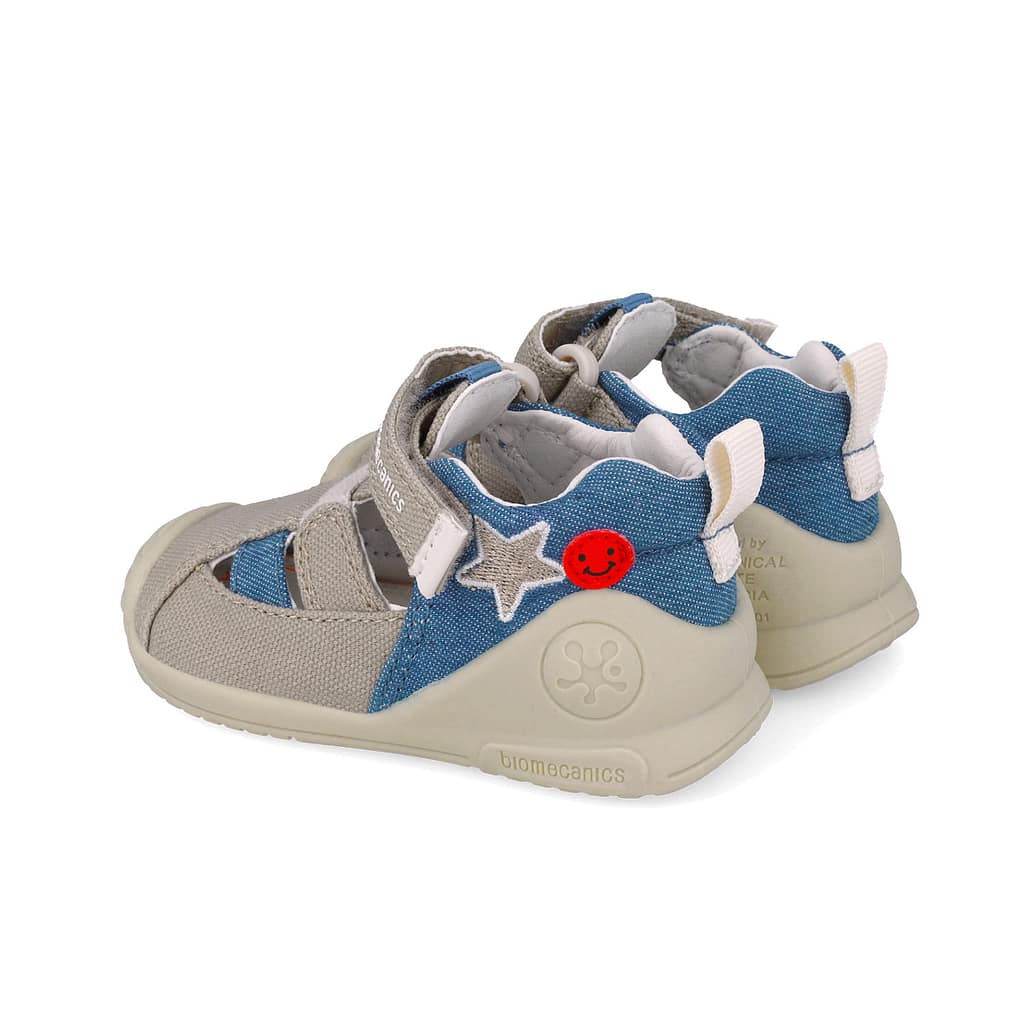 Children's blue and beige sneakers with star patch and red smiley button on the side.