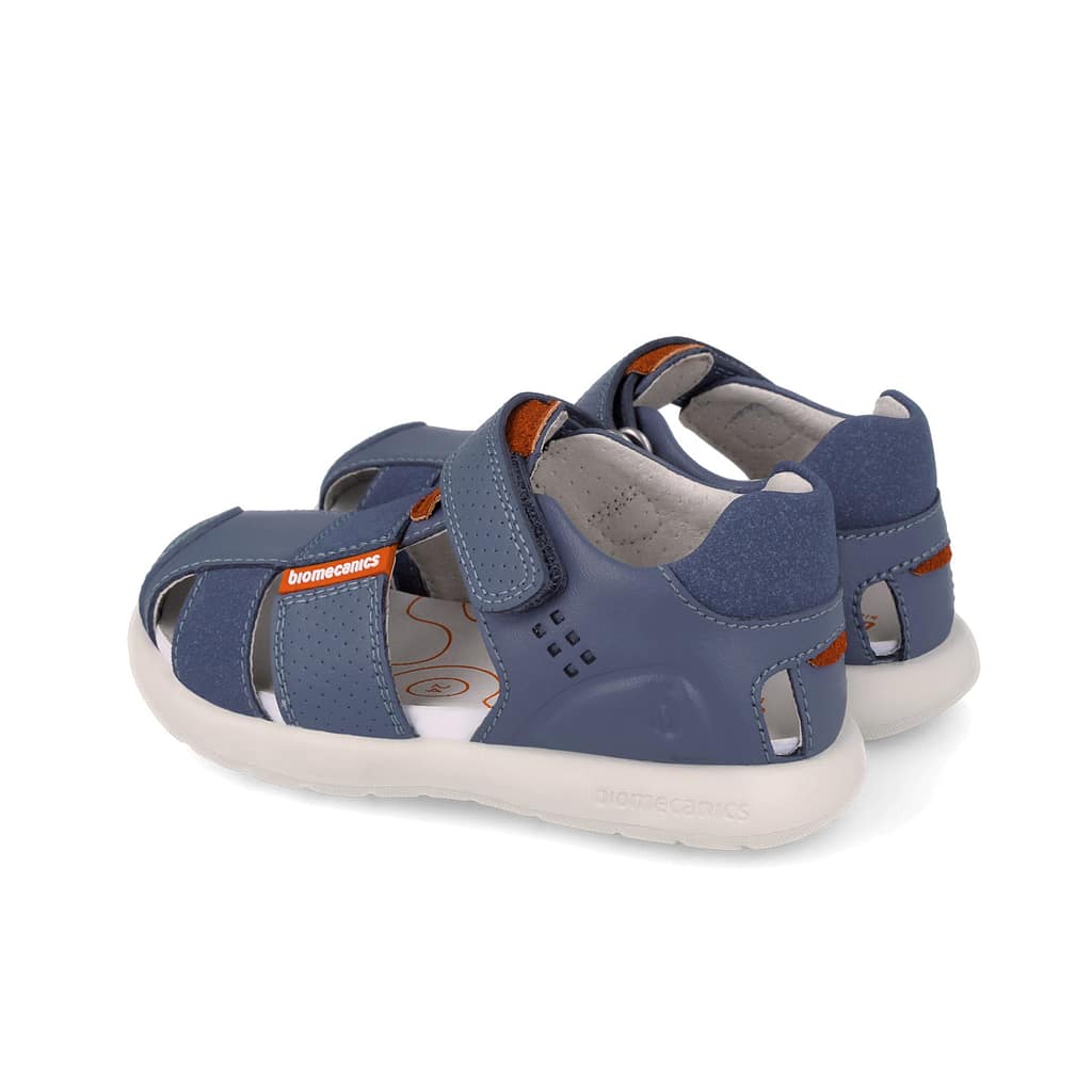 Blue kids' sandals with adjustable Velcro straps, orange accents, and a white cushioned sole featuring Biomecanics branding on the strap.