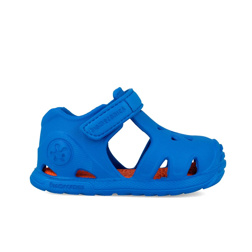 Blue children's sandal with an adjustable Velcro strap and orange footbed visible inside the open upper area.