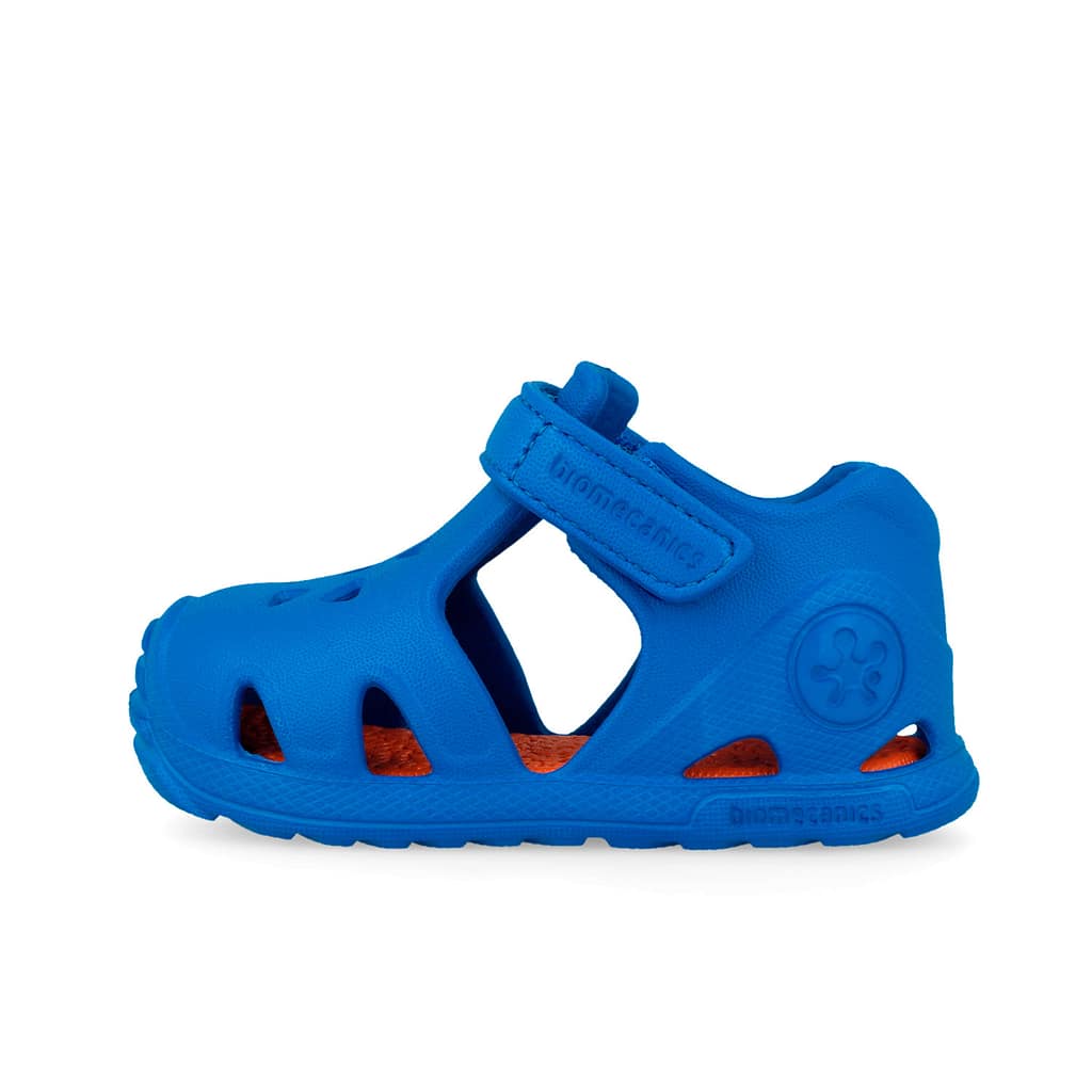 Blue kids' closed-toe sandal with multiple cutouts and a Velcro strap (Crocs-style) seen from the side